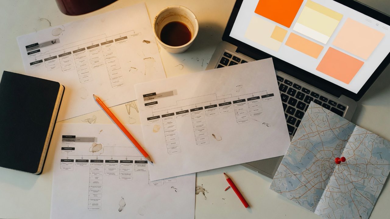 Workbench with sitemap printouts, a map pin, and a laptop